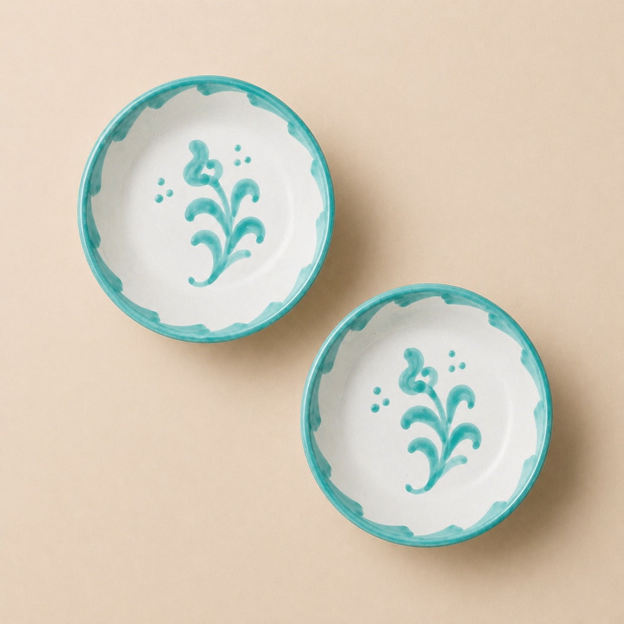 Two ceramic bowls with turquoise rims and floral designs on a beige background