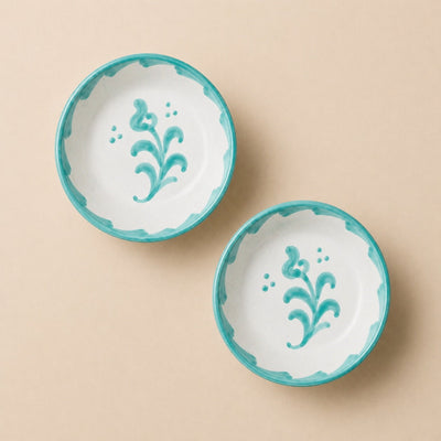 Two ceramic bowls with turquoise rims and floral designs on a beige background