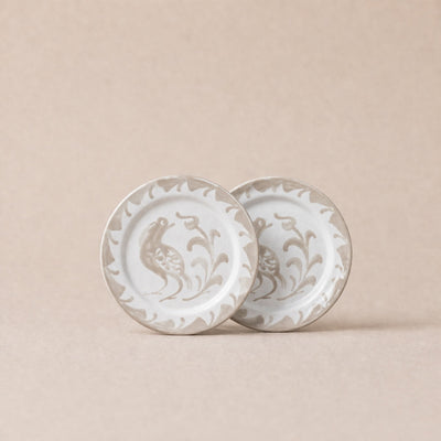 Two ceramic plates with decorative patterns on a beige background