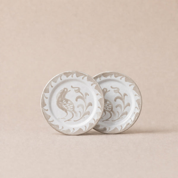 Two ceramic plates with decorative patterns on a beige background