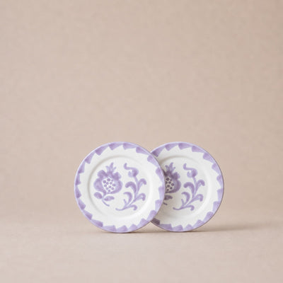 Two ceramic plates with purple floral patterns on a beige background