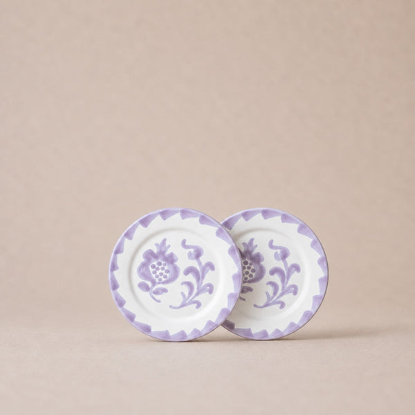 Two ceramic plates with purple floral patterns on a beige background