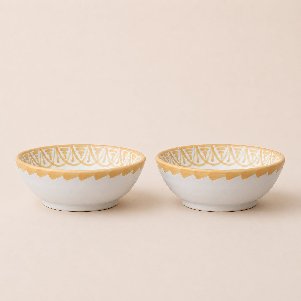Two ceramic bowls with gold lace patterns on a beige background