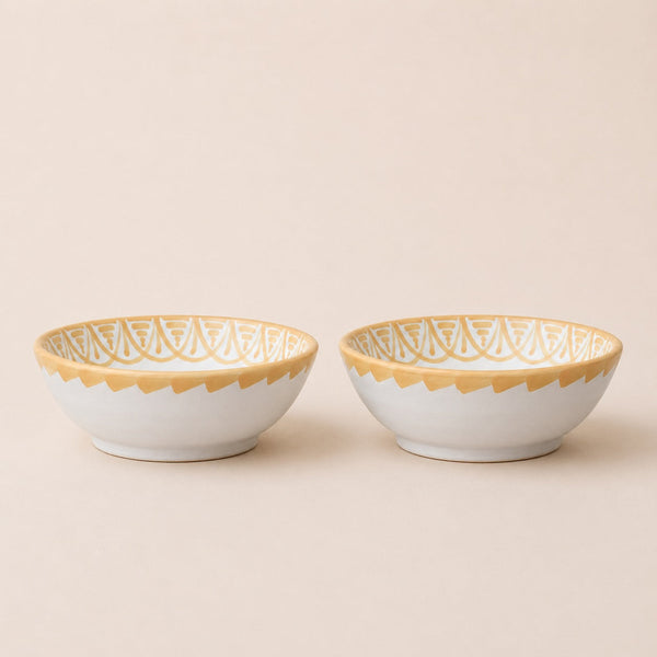 Two ceramic bowls with gold lace patterns on a beige background