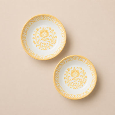 Two ceramic plates with yellow floral patterns on a beige background