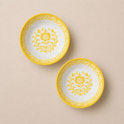 Two white plates with yellow floral patterns on a beige background