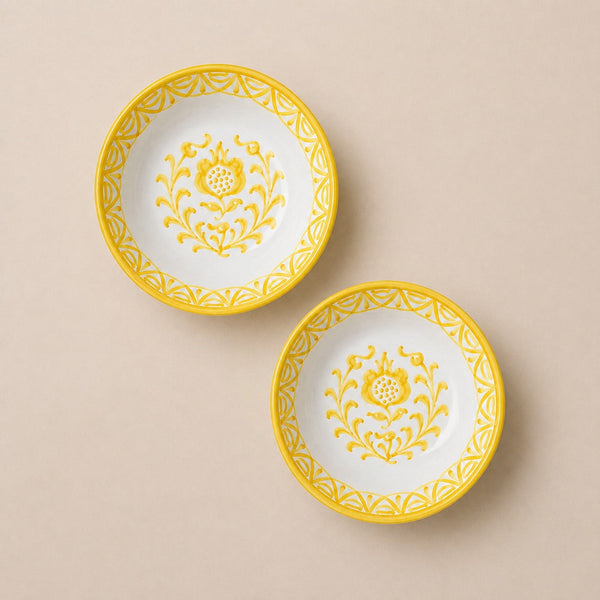 Two white plates with yellow floral patterns on a beige background