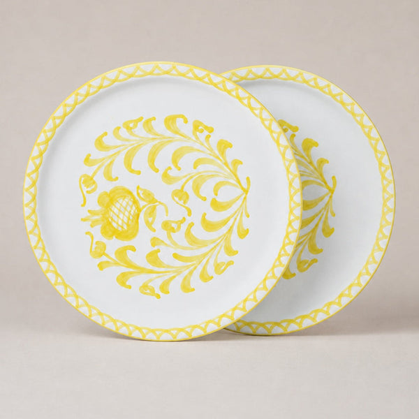 Two traditional dinner plates with yellow floral patterns on a beige background