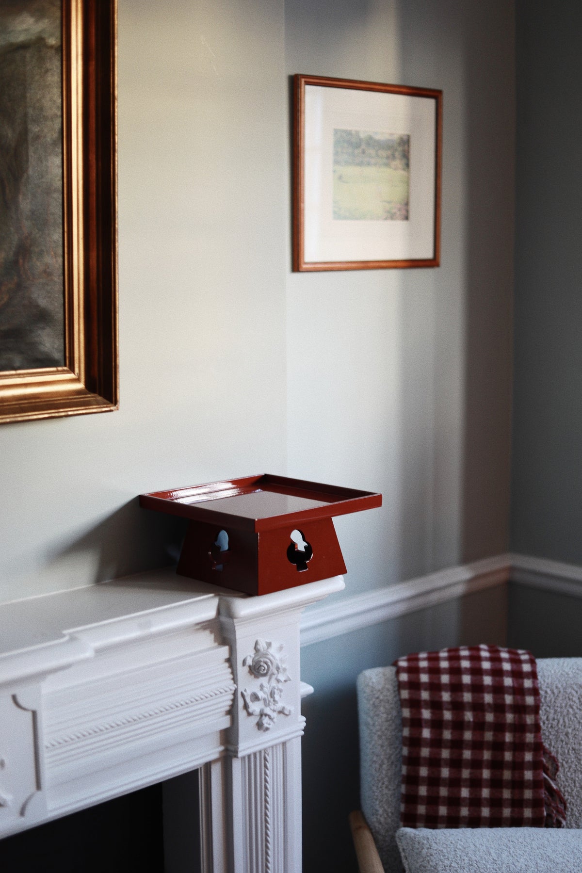 Vinidec elevated tray in rich red gloss finish with playing card cutouts, styled on a white fireplace mantel in an elegant London interior