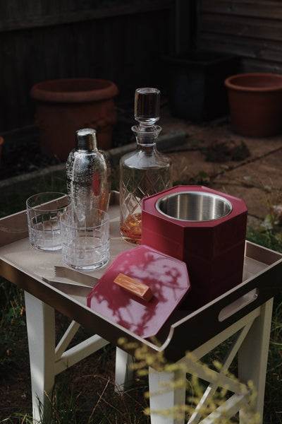 VINIDEC lacquer ice bucket styled on a serving tray with cocktail glasses, shaker and decanter in an outdoor home bar setting.