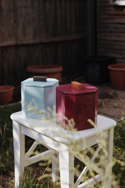 Blue and burgundy VINIDEC lacquer ice buckets displayed outdoors on a white side table.