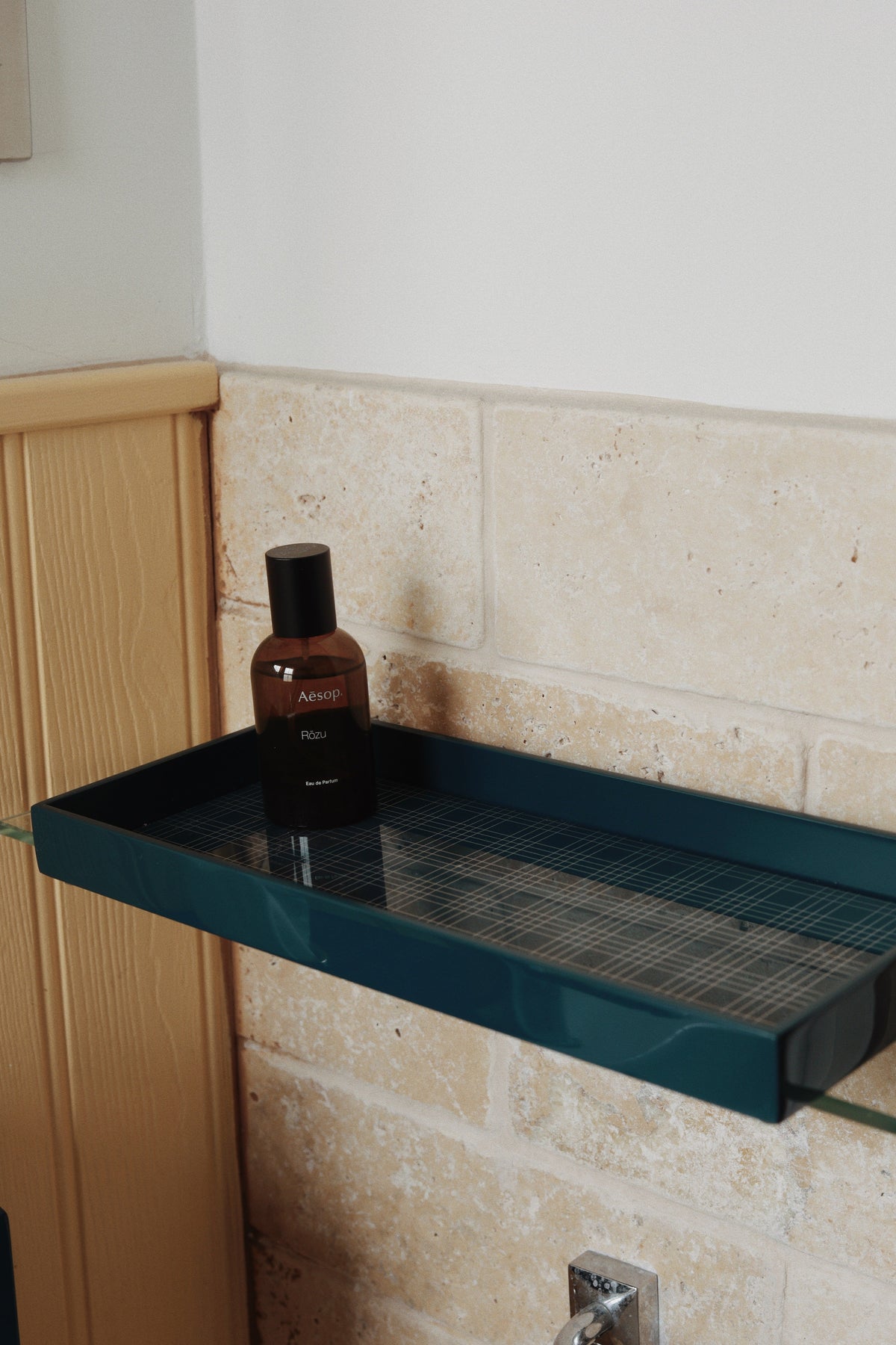 Vinidec slim dark teal linear lacquered tray with grid insert holding perfume on a narrow glass bathroom shelf