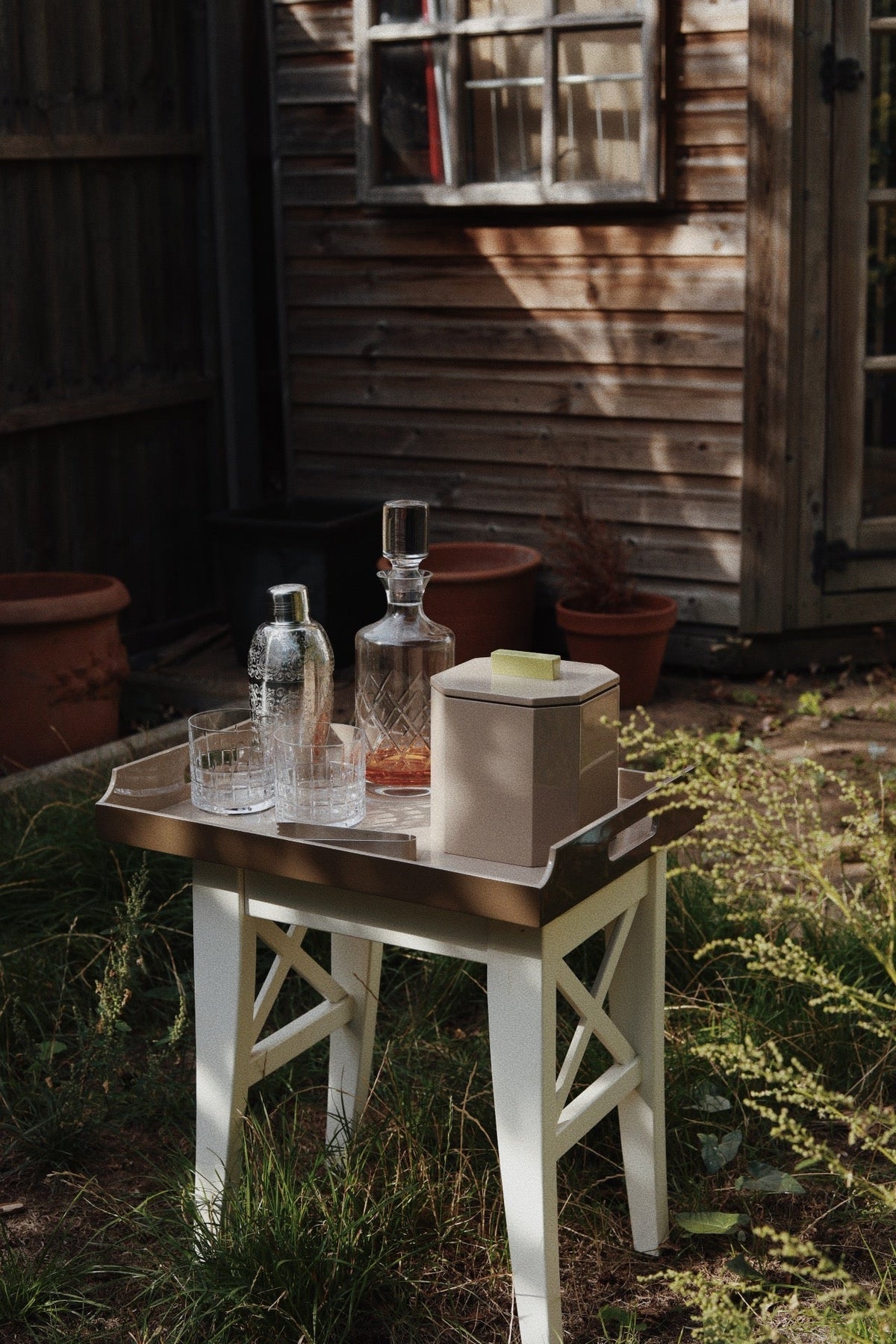 Luxury VINIDEC ice bucket on a lacquer serving tray with whisky decanter and glasses in a garden entertaining setup.