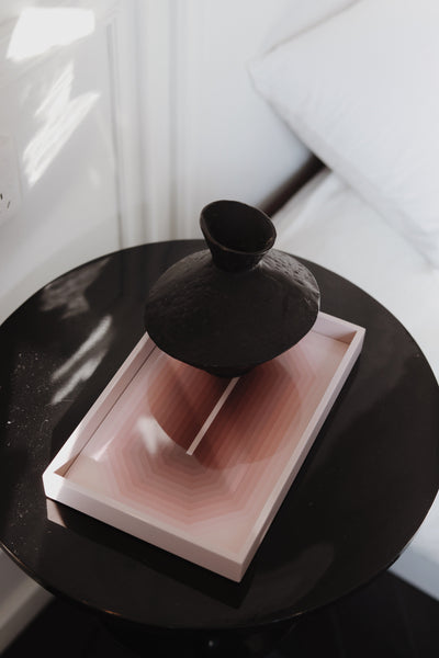 Small sand pink Chiaroscuro high-gloss lacquer tray styled with a black ceramic vase on a bedside side table