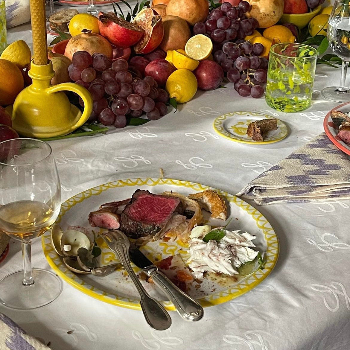 Dinner table set with a plate of food, fruits, and candles on a checkered tablecloth. - lifestyle