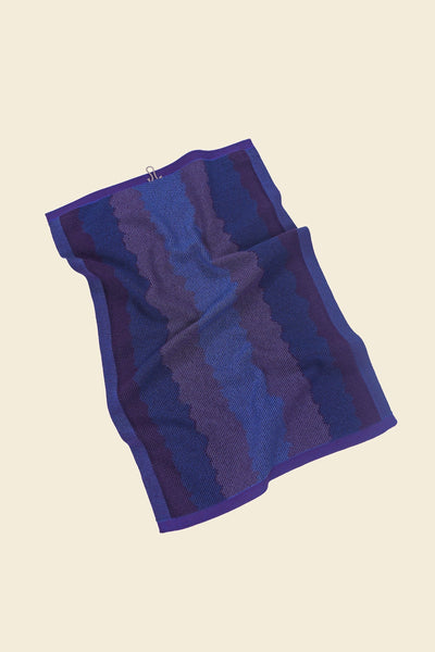 back view of purple knit organic cotton kitchen towel with wavy pattern with folds