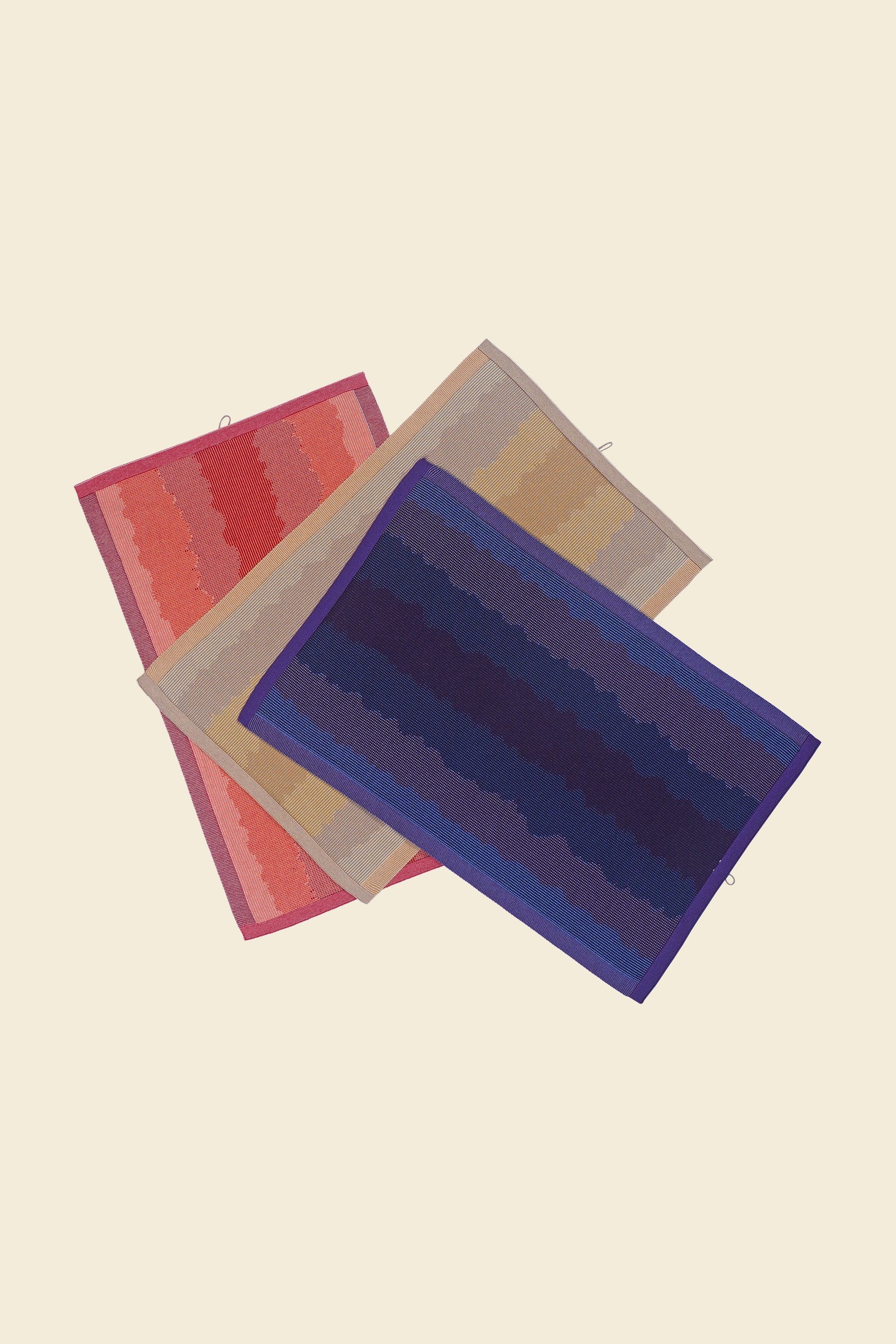 front view of purple, red and yellow knit organic cotton kitchen towel set with wavy pattern stacked