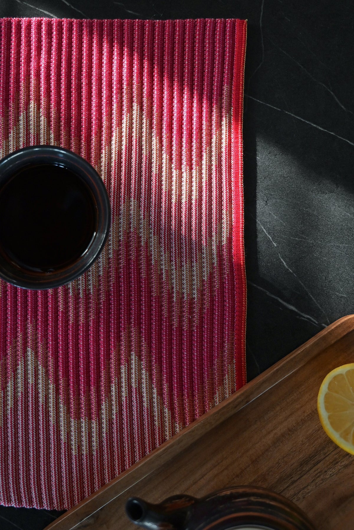 corner detail of red/yellow knit table mat in organic cotton and viscose with wavy pattern