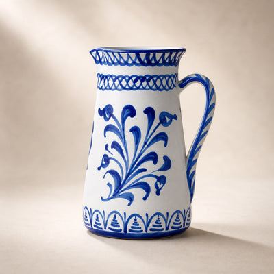 White ceramic pitcher with blue floral patterns on a beige background.