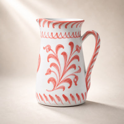 White ceramic pitcher with red floral patterns on a beige background