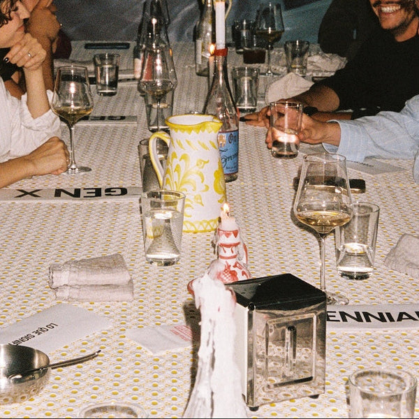 People sitting around a table with wine glasses and a pitcher, with 'GEN X' and 'ENNIA' branding visible. - lifestyle
