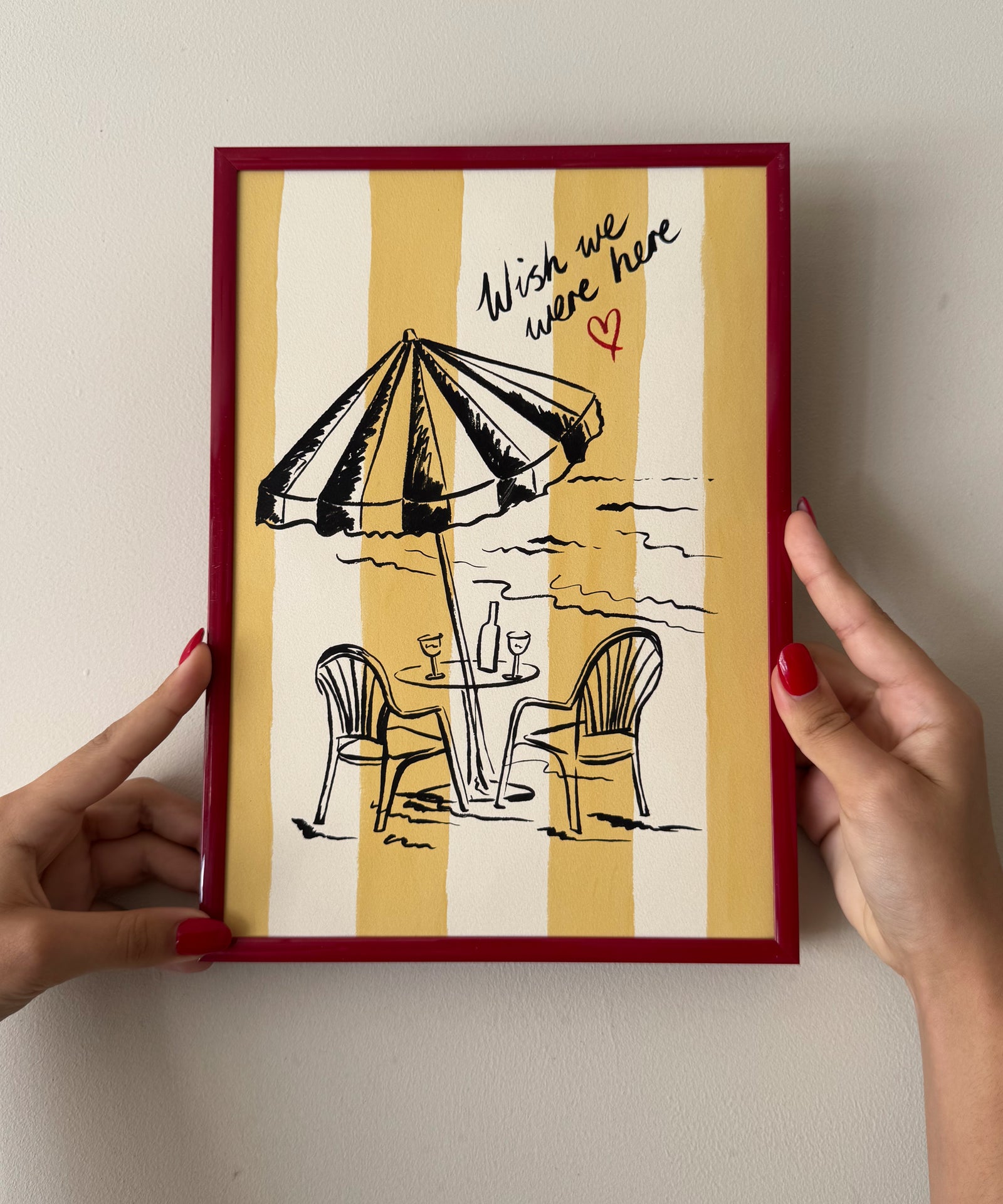 "Wish We Were Here" ink sketch print of a beach parasol and plastic chairs on a striped background, seaside wall art in frame