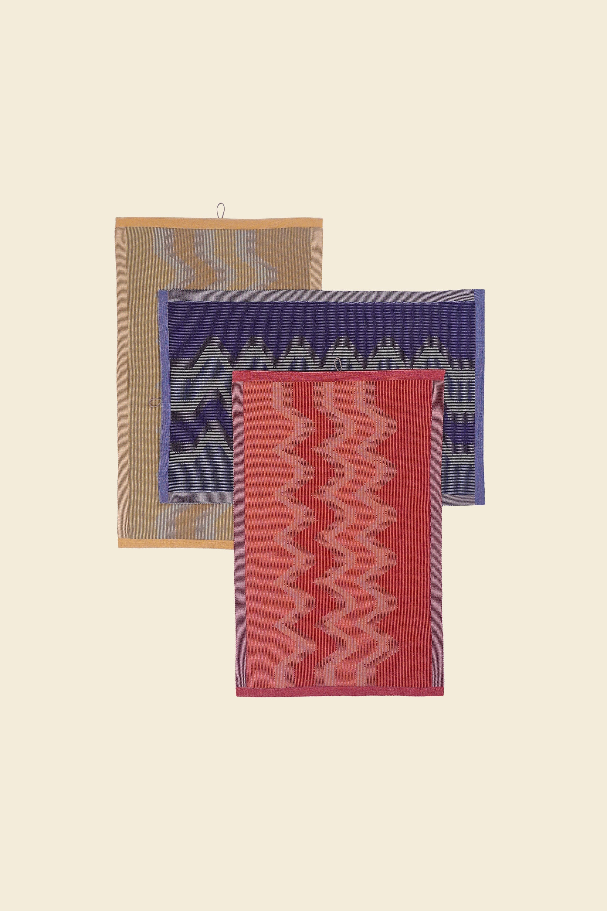 top view of yellow, red and purple knit organic cotton kitchen towel set with zig zag pattern stacked