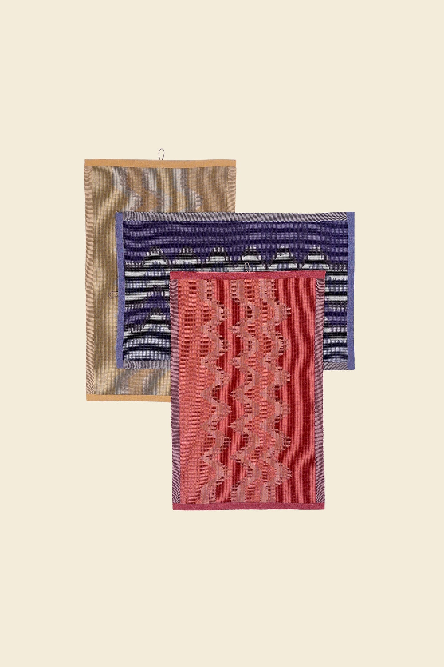 top view of yellow, red and purple knit organic cotton kitchen towel set with zig zag pattern stacked