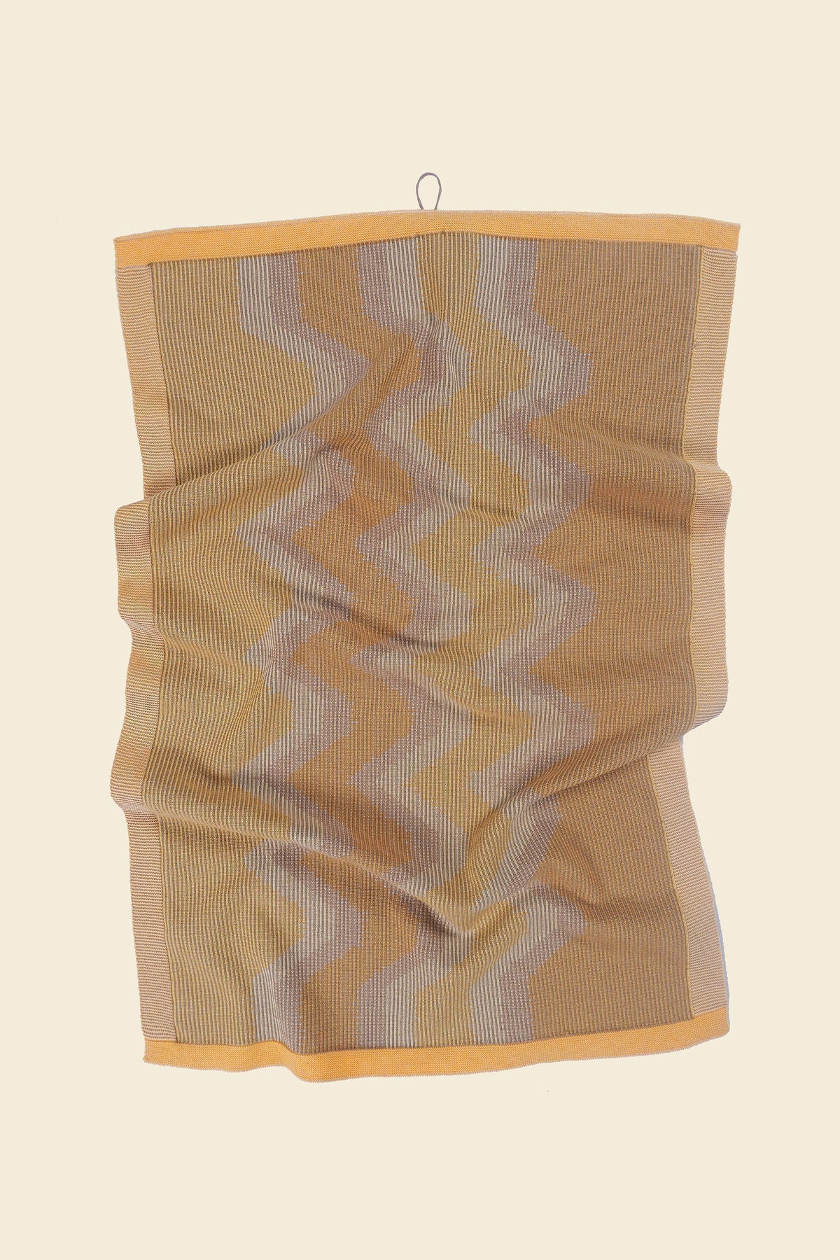 front view of yellow knit organic cotton kitchen towel with zig zag pattern with folds