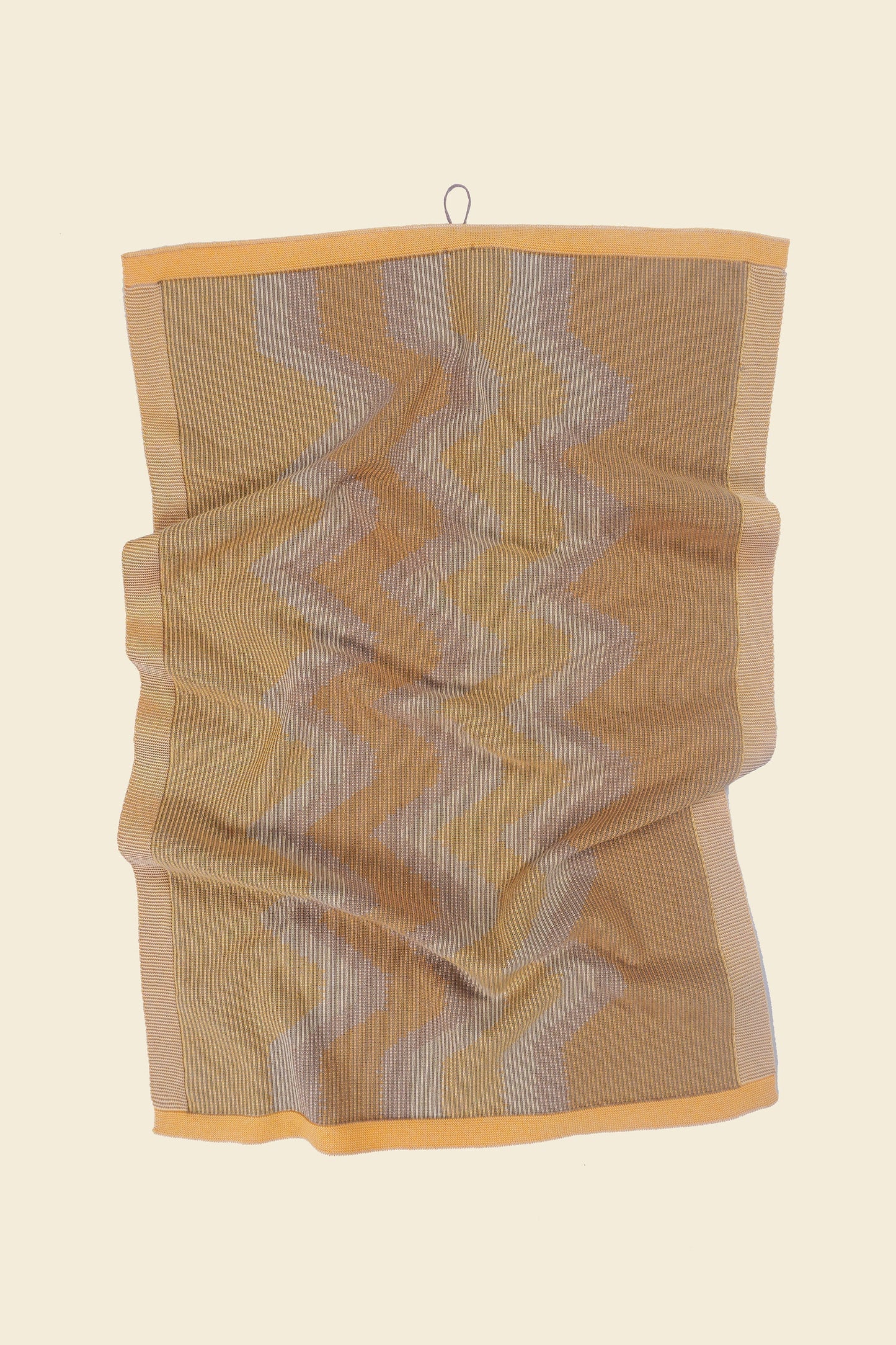 front view of yellow knit organic cotton kitchen towel with zig zag pattern with folds