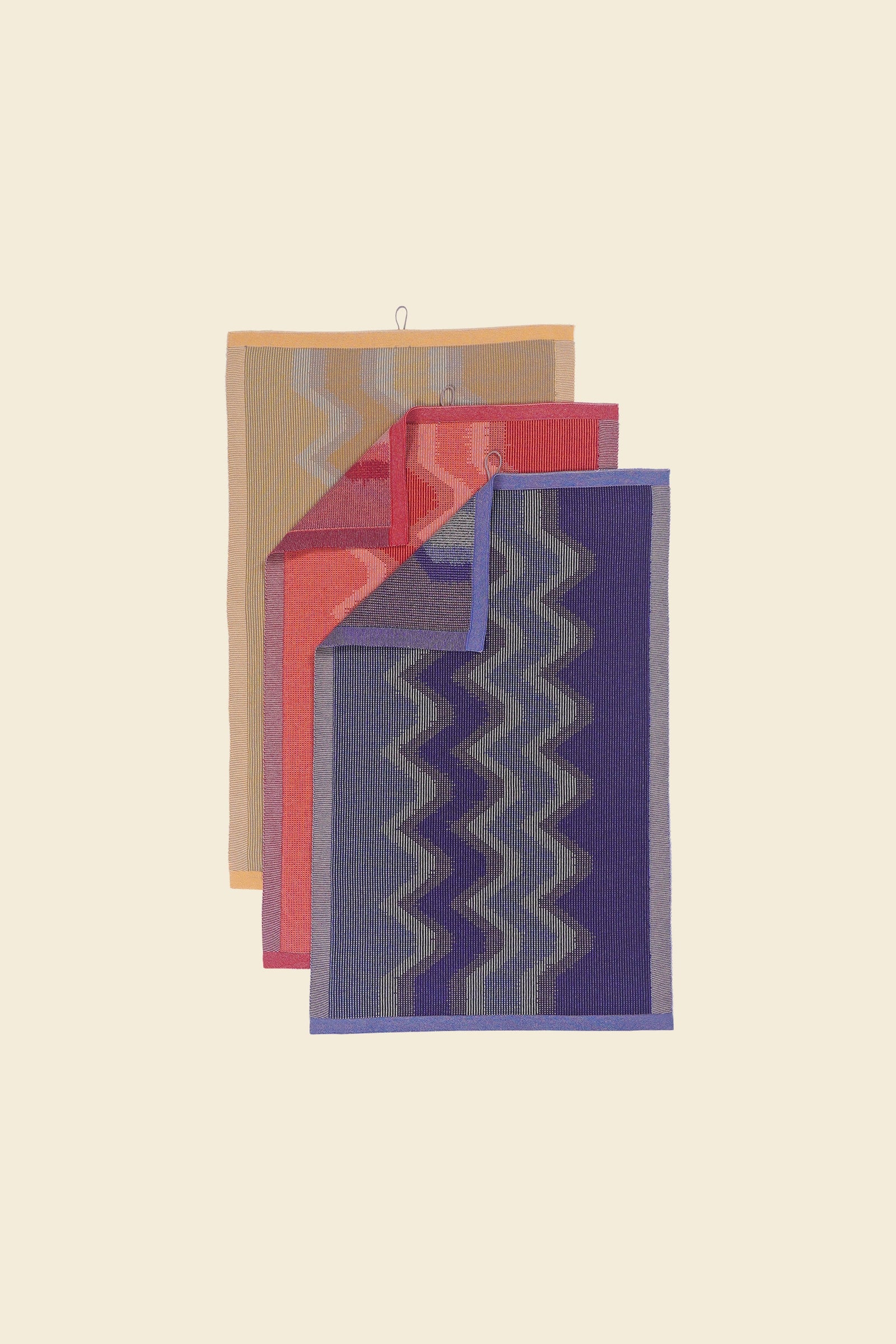 top view of yellow, red and purple knit organic cotton kitchen towel set with zig zag pattern corners folded