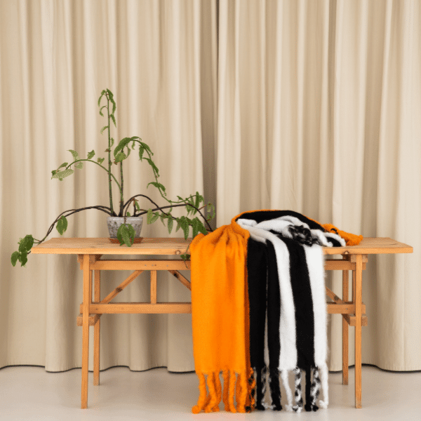 Viso Mohair Blanket Black Orange & White Horizontal Stripes on table
