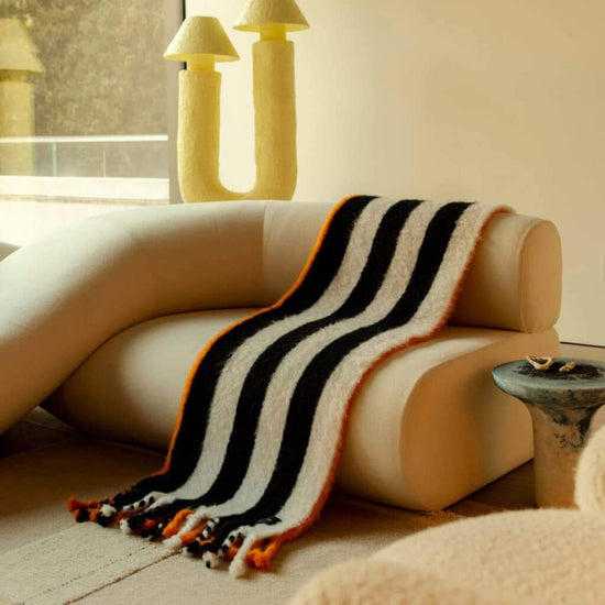 Load image into Gallery viewer, Viso Mohair Blanket Black Orange &amp;amp; White Horizontal Stripes on sofa
